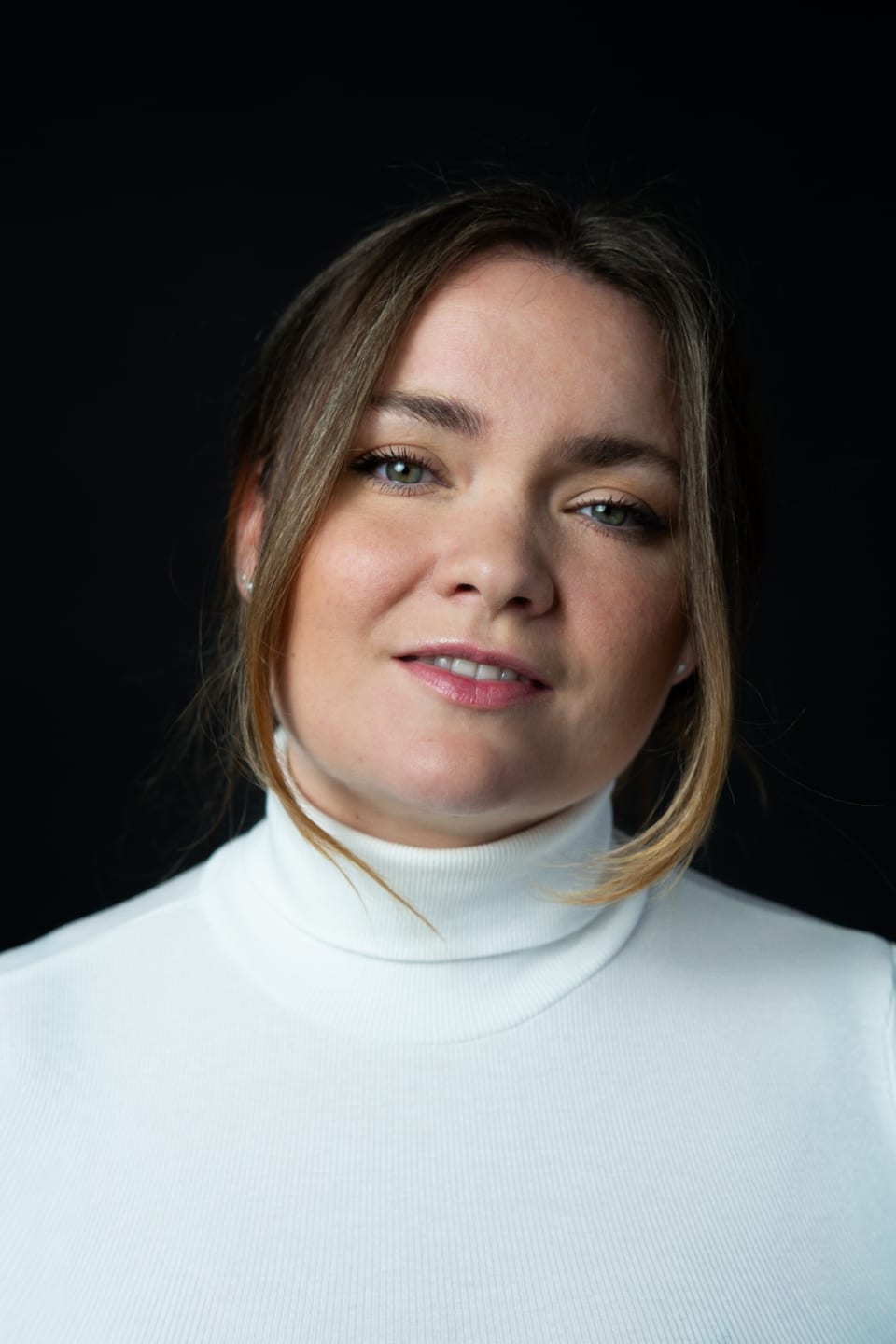 Portrett af Ylfu Marín í hvítri rúllukragapeysu, svartur bakgrunnur